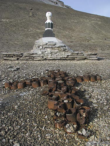 ArcticQ_20080827_110728_508_S.jpg - An cross made of some of the cans that are suspected of contributing to the death of Franklin and his men points like an arrow to their monument on Beechy Island, Nunavut, Canada.