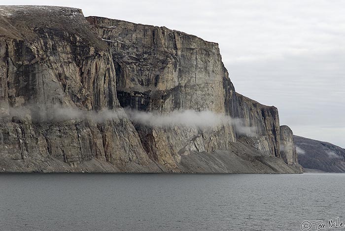 ArcticQ_20080906_090258_223_20.jpg - A small cloud or remnant of sea fog hovers on the face of a major formation in Sam Ford Fjord Baffin Island, Nunavut, Canada.